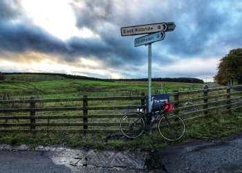 Cycle in front of sign post showing East Klbriide 8 miles and Strathaven 4 miles