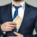 Main suit tucking a brown envelope into his jacket pocket.