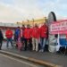 postal workers on the pavement,'with a large sign 'Honk if you back us!@