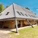 large building with a low sloping roof and posts seemingly holding the roof in place going into the ground