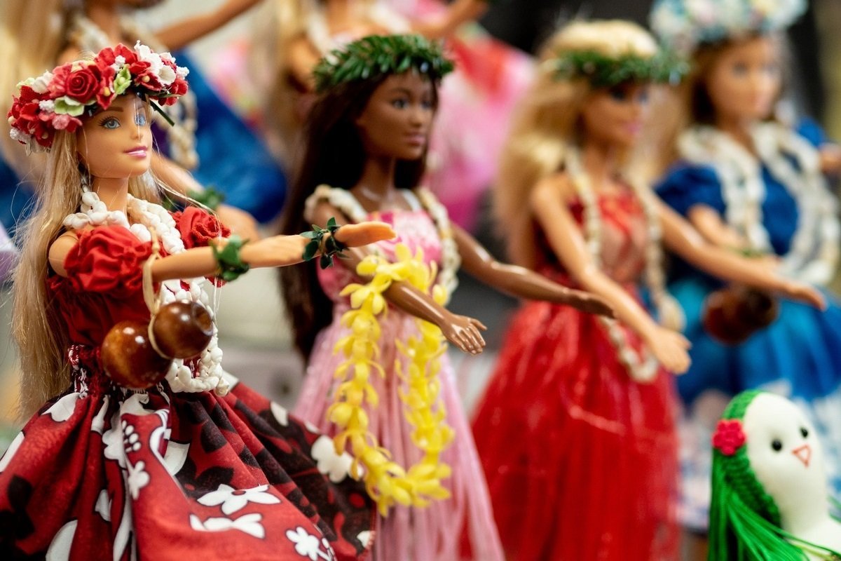 A row of barbies in different colour dresses, with flowery or green leaved wreaths on their heads