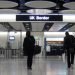 Two peaople in dark clothes and hoodies walking toward the UK Border customs area at Heathrow airport