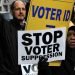People demonstrating holding placards saying 'stop voter suppression' and 'voter ID'