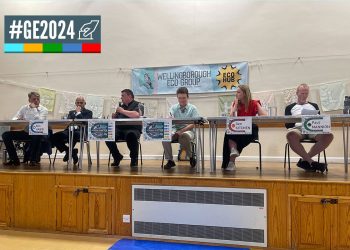 Six people sitting behind tables on a podium