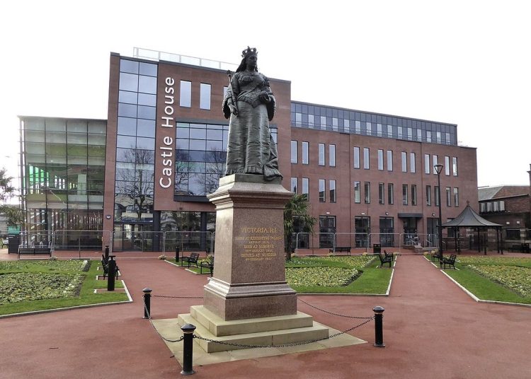 Large building set in a park with a statue in front