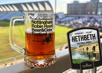 A glass of amber beer at Nottingham Robin Hood Beer & Cider Festival, alongside the Hethbeth ale pump clip featuring an image of the old Trent Bridge.